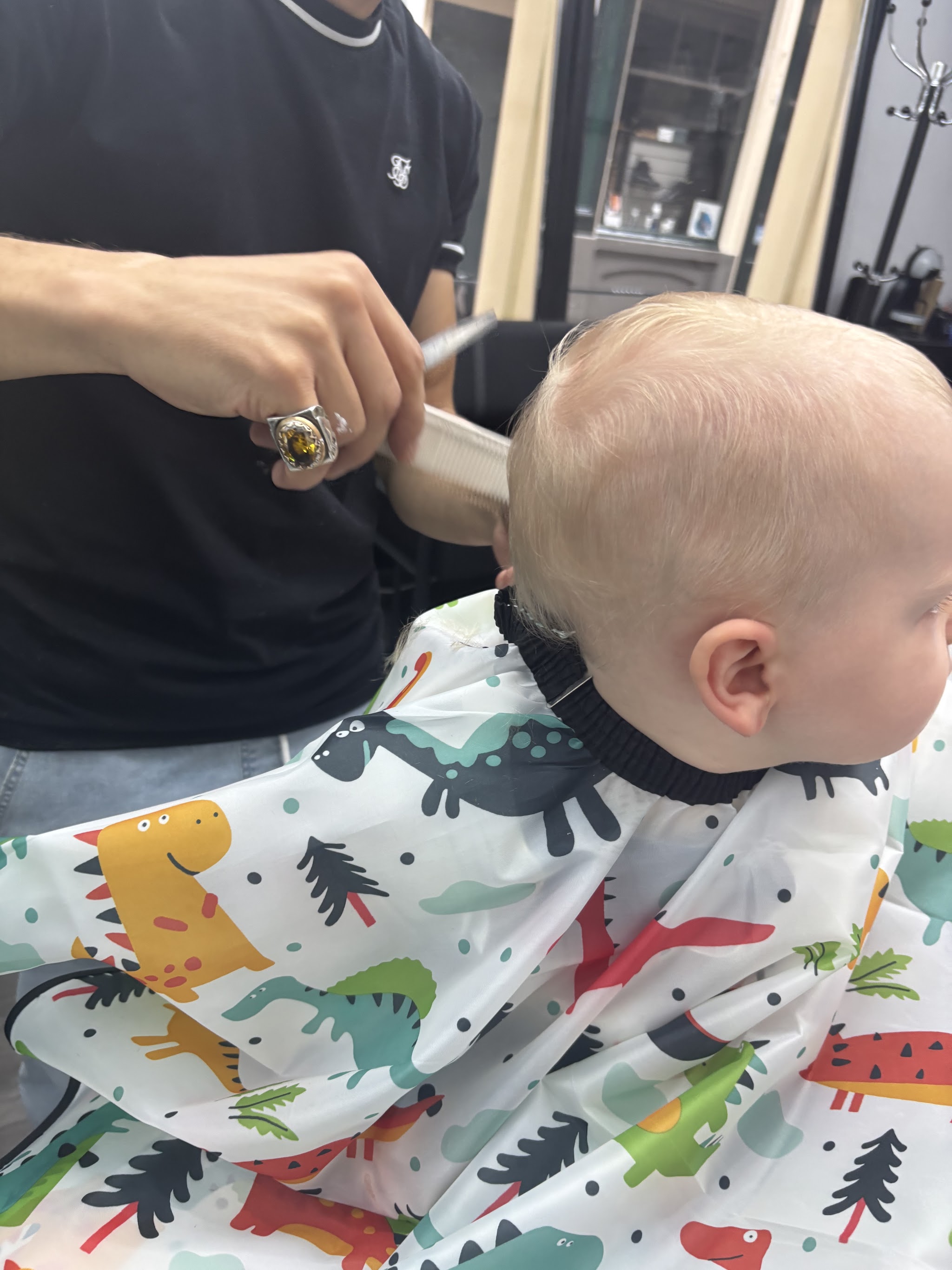 Een kleine klant met dinosauruscape tijdens het knippen