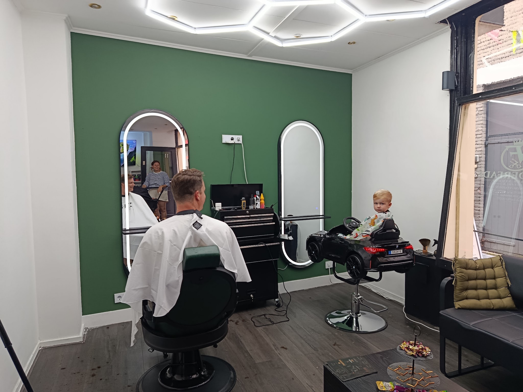 Het interieur van VANDERFADE: groene muur, verlichte spiegels en de kinderstoel in autovorm