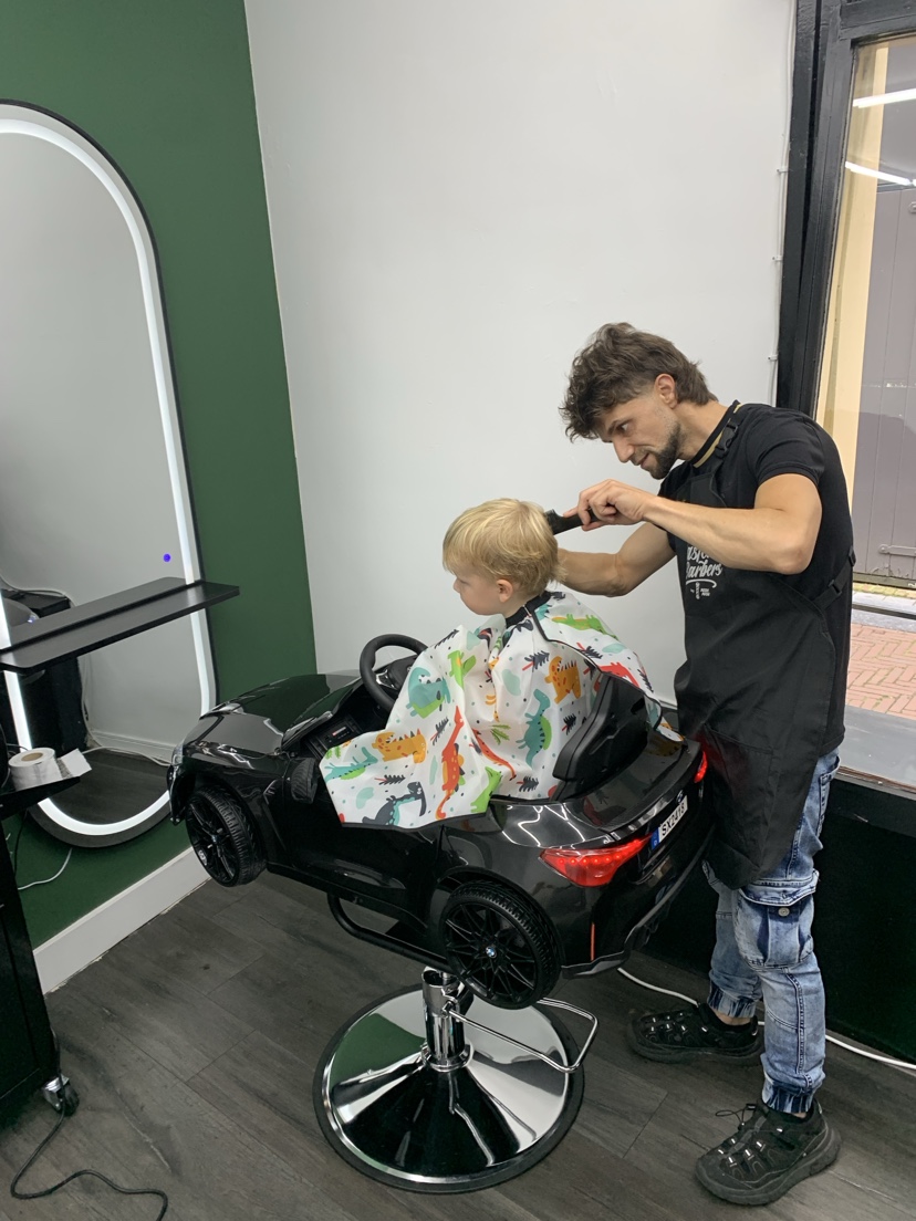 De barber knipt een peuter in de autostoel